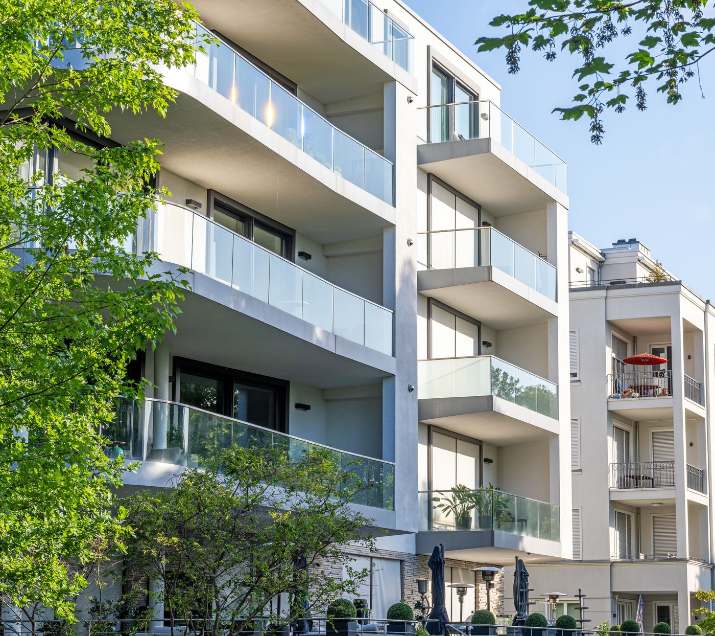 Wohnhaus mit umlaufenden Balkonen, gerahmt von Baumkronen